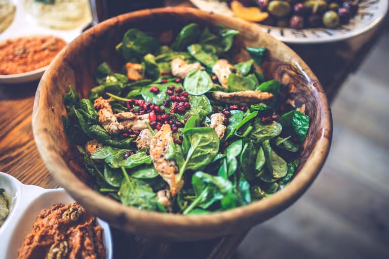 A healthy chicken salad bowl with spinach, pomegranate seeds, and chicken fillet in a wooden bowl - representing the protein and fiber-rich meals in a 5-day weight loss meal plan for women over 40