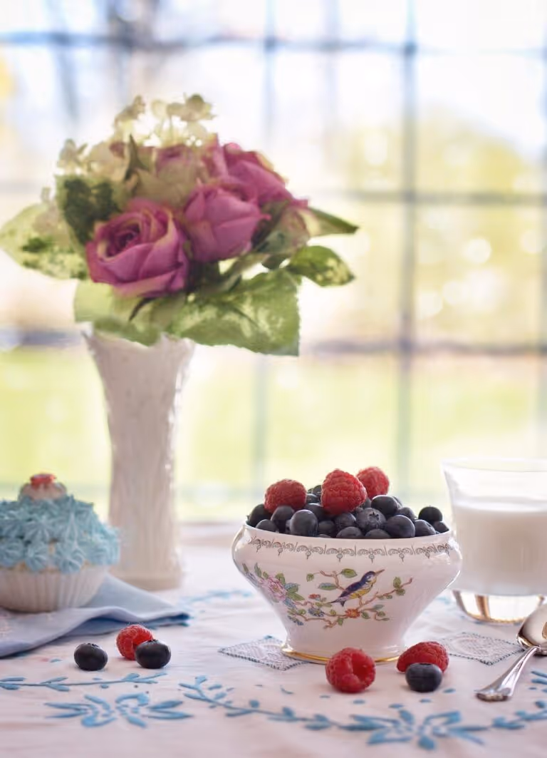 Bowl of fresh blueberries and raspberries on a wooden table - perfect for berry breakfast recipes