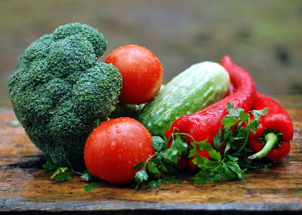 Colorful fresh vegetables with water droplets on a wooden table, representing the back-to-basics approach to healthy eating for longevity