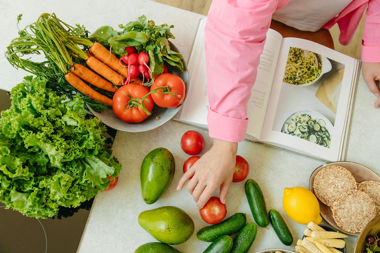 Fresh colorful vegetables and a cookbook on a wooden table, representing anti-inflammatory ingredients for healthy meal prep recipes