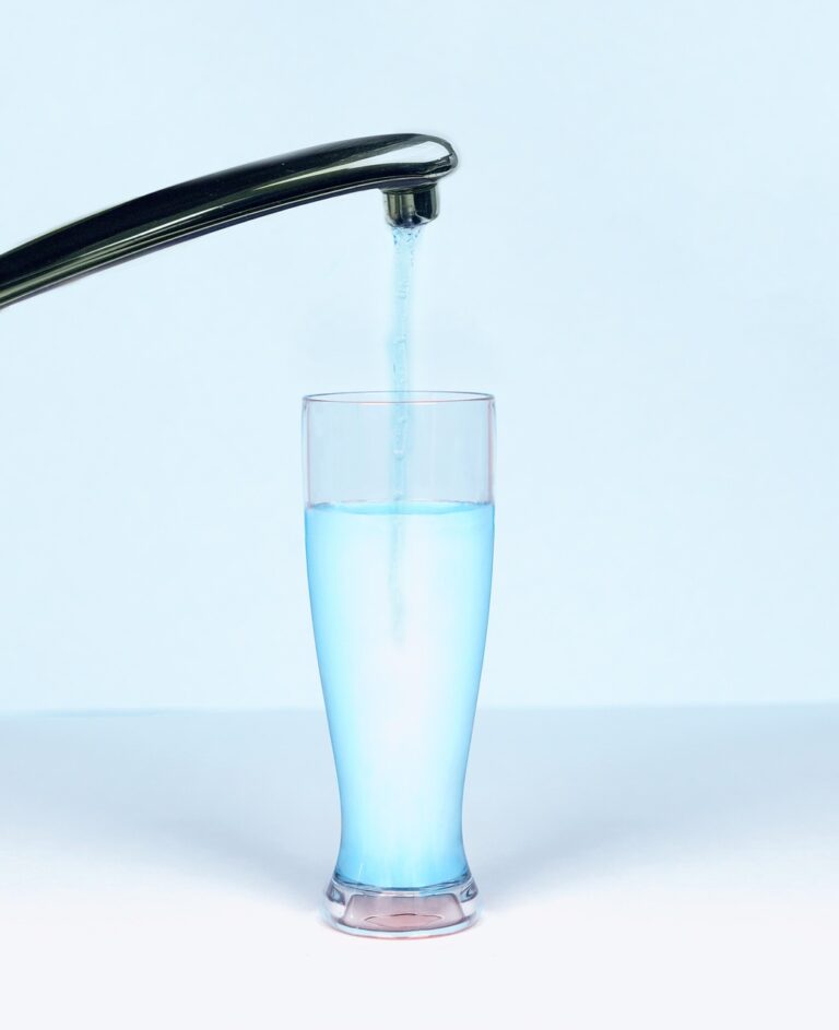 Clear drinking water being poured from a faucet into a glass, representing tap water quality and nanoplastics concerns