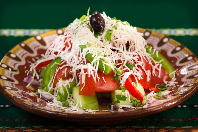 Fresh Mediterranean salad with tomatoes, olives, peppers, feta cheese, and basil on a wooden table - perfect for a healthy Mediterranean lunch recipe
