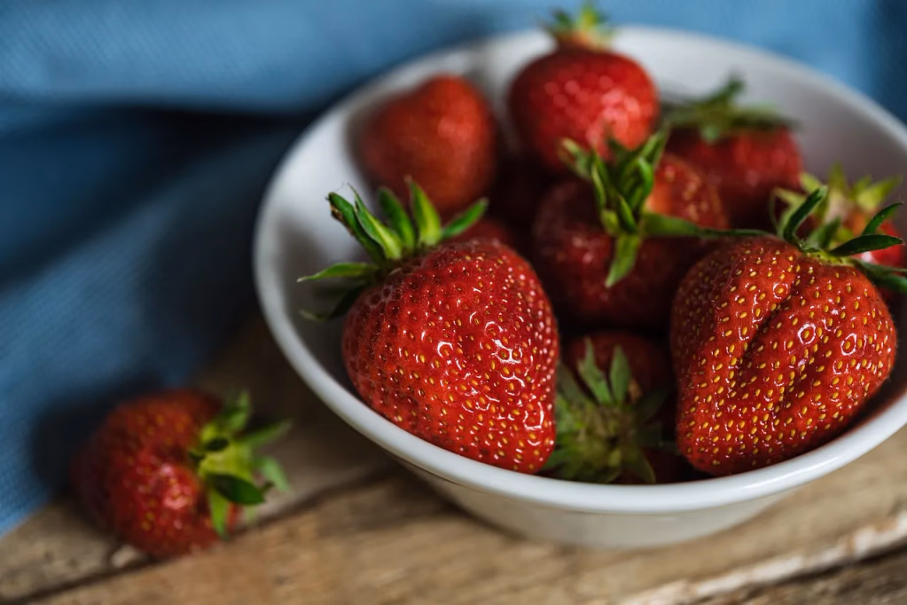 Fresh ripe strawberries on a light surface, representing peak summer seasonal produce for a healthy 7-day summer meal plan with grocery list and Sunday prep guide.