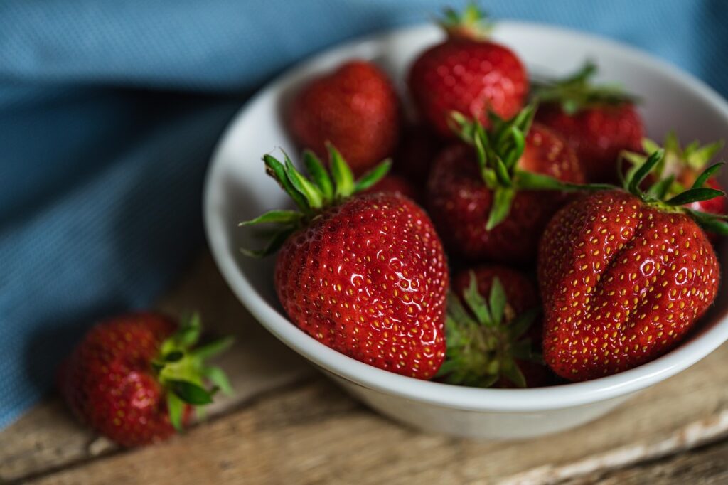 Fresh ripe strawberries on a light surface, representing peak summer seasonal produce for a healthy 7-day summer meal plan with grocery list and Sunday prep guide.