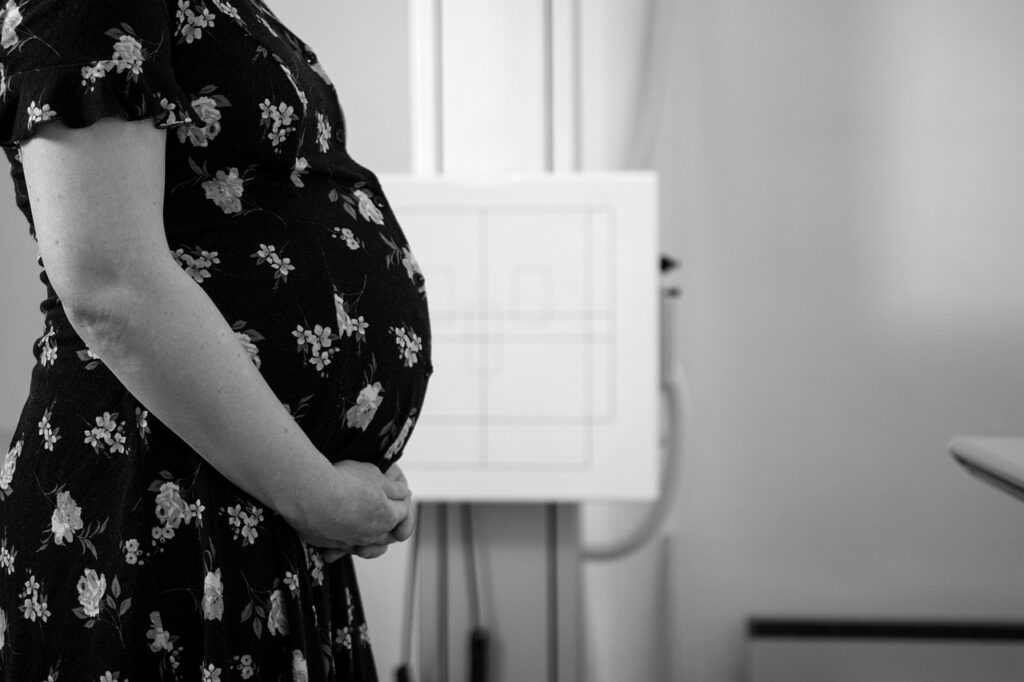 A pregnant Black woman standing in a medical clinic setting, representing Black maternal health and the importance of equitable healthcare during pregnancy