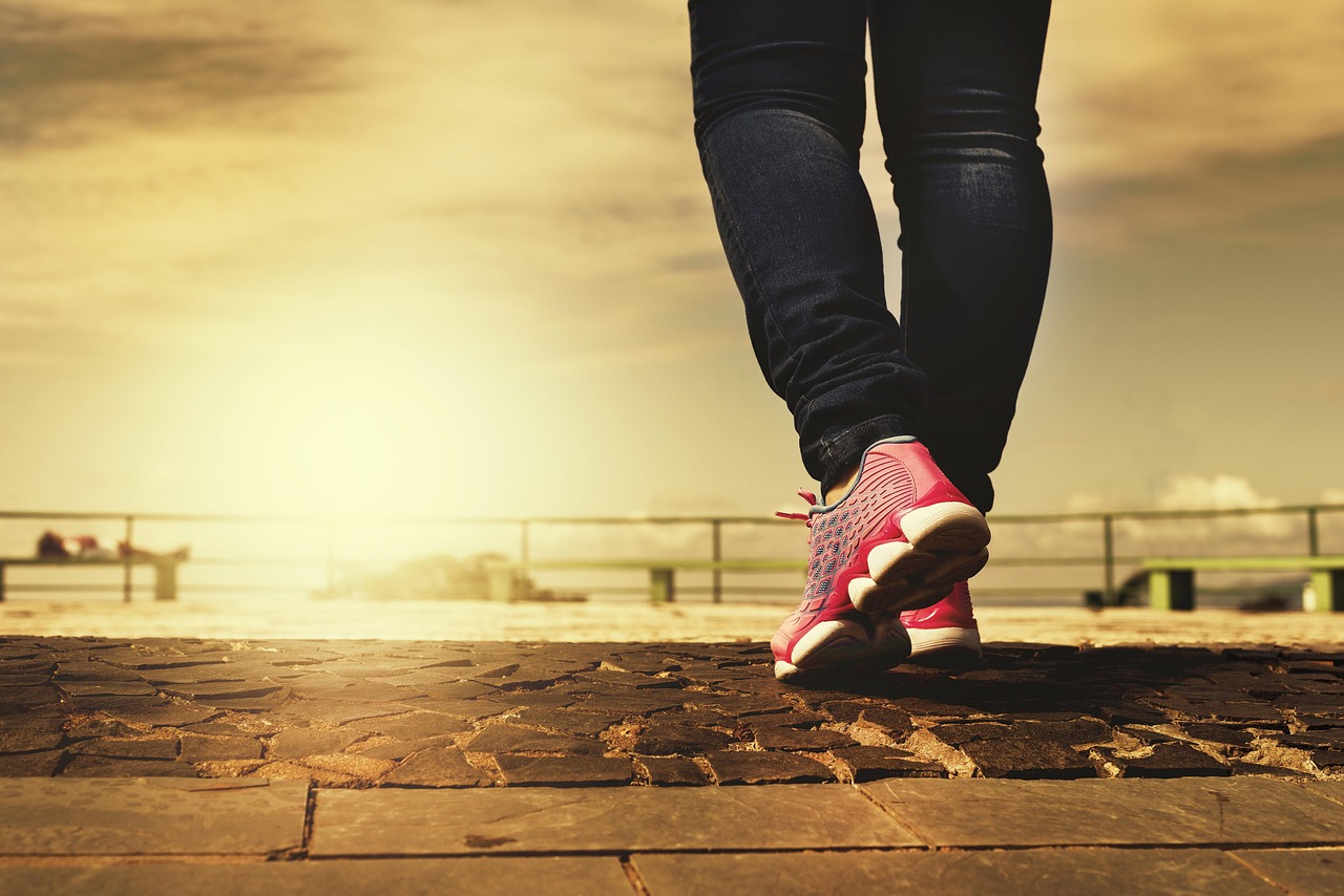 Woman wearing comfortable sneakers while walking on a scenic path, representing the best walking shoes for all-day pain-free comfort