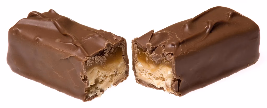 A chocolate bar being broken in half, symbolizing the sweet food cravings that research has linked to early cognitive changes in some forms of dementia. Image represents the article topic of dementia food cravings.