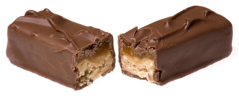 A chocolate bar being broken in half, symbolizing the sweet food cravings that research has linked to early cognitive changes in some forms of dementia. Image represents the article topic of dementia food cravings.