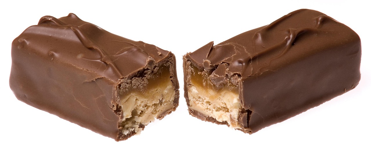 A chocolate bar being broken in half, symbolizing the sweet food cravings that research has linked to early cognitive changes in some forms of dementia. Image represents the article topic of dementia food cravings.