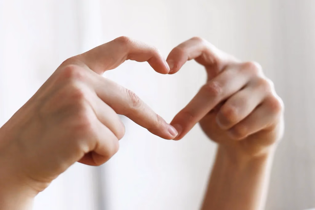 Hands forming a heart shape representing heart health and self-care during menopause, featuring strength training and HIIT for cardiovascular wellness
