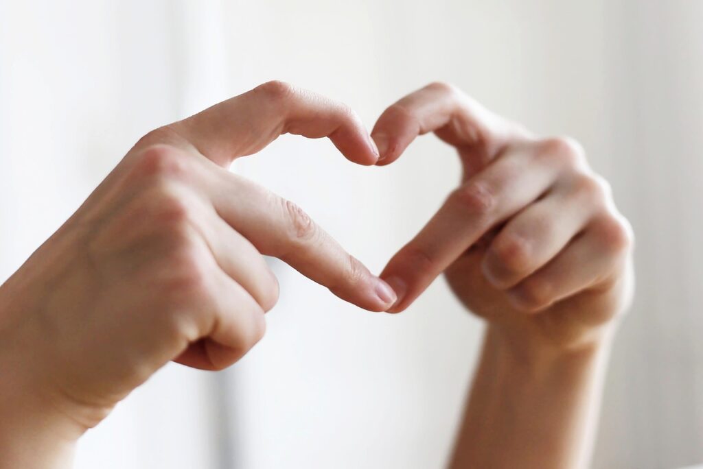 Hands forming a heart shape representing heart health and self-care during menopause, featuring strength training and HIIT for cardiovascular wellness