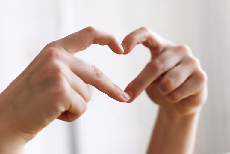 Hands forming a heart shape representing heart health and self-care during menopause, featuring strength training and HIIT for cardiovascular wellness