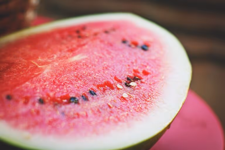 Fresh sliced watermelon on a white surface - a hydrating fruit rich in lycopene and water, ideal for sun exposure recovery after a long day in the heat