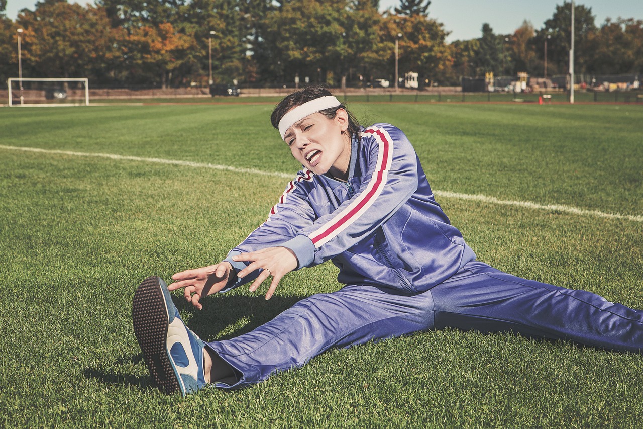Young woman stretching on a grassy field in athletic wear, representing exercise personality type and finding the right workout for your unique traits