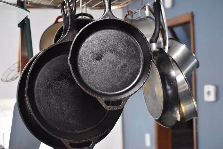 A black cast iron skillet on a stovetop containing golden pancakes with fresh berries and syrup, demonstrating a well-seasoned cast iron pan in use