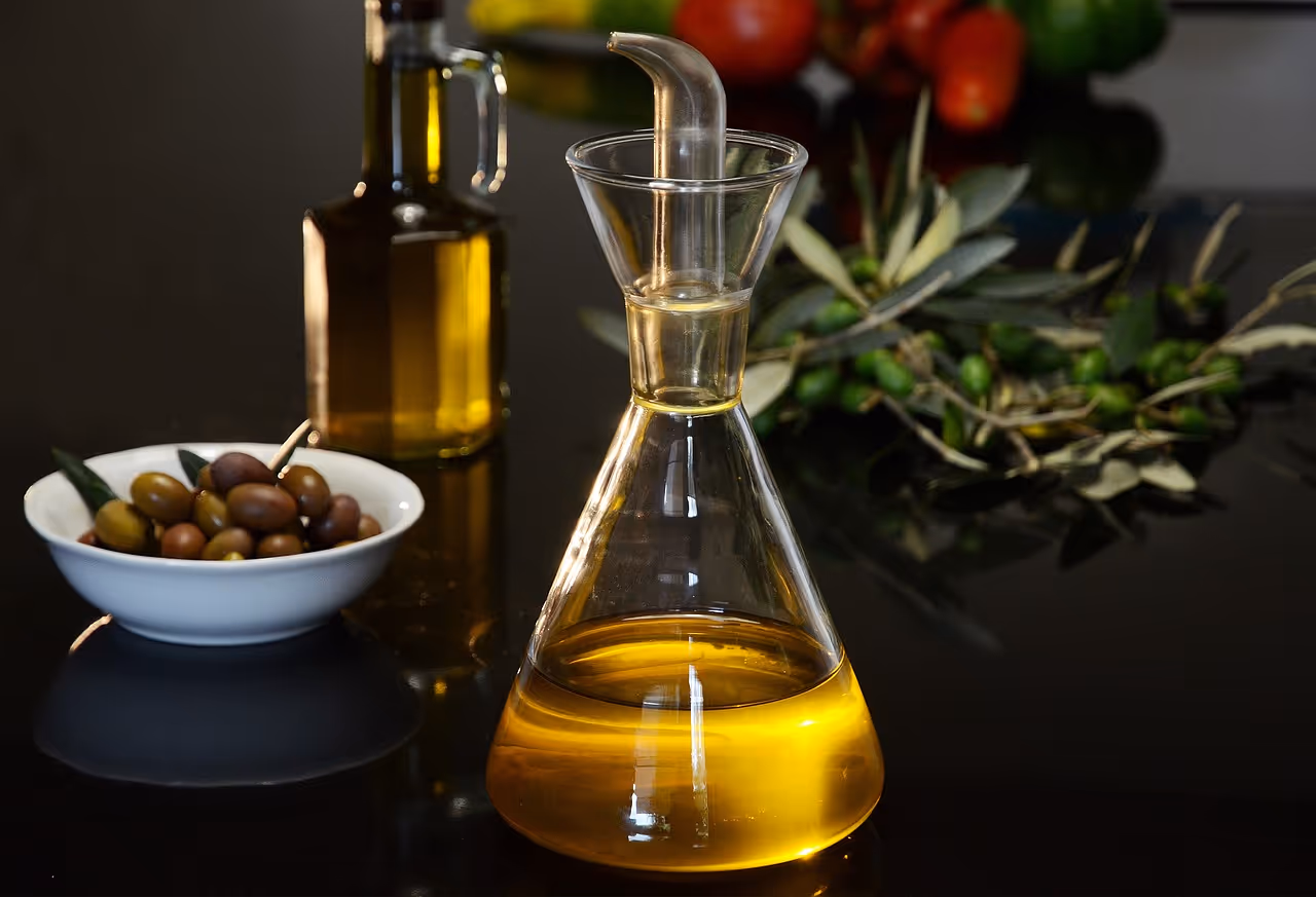 A bottle of extra virgin olive oil surrounded by fresh olives on a wooden surface, representing high-polyphenol olive oil for heart health