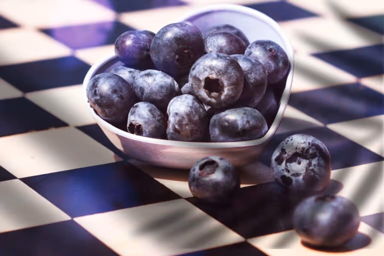 Blueberries in a heart-shaped ceramic bowl on a black and white checkered tablecloth, representing a heart healthy breakfast with antioxidant-rich fruit