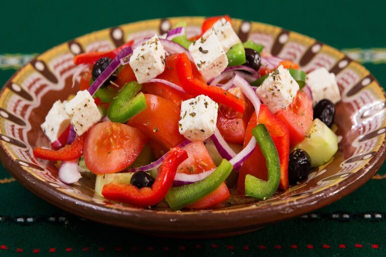 Fresh Mediterranean Greek salad with feta cheese, tomatoes, cucumbers, olives, and peppers on a wooden table - perfect pairing for feta brined chicken bowls