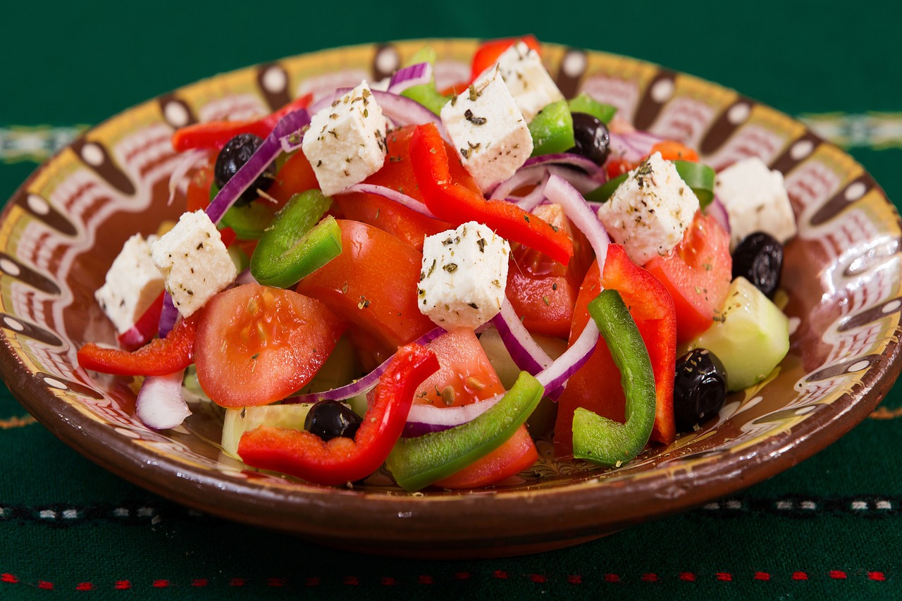 Fresh Mediterranean Greek salad with feta cheese, tomatoes, cucumbers, olives, and peppers on a wooden table - perfect pairing for feta brined chicken bowls