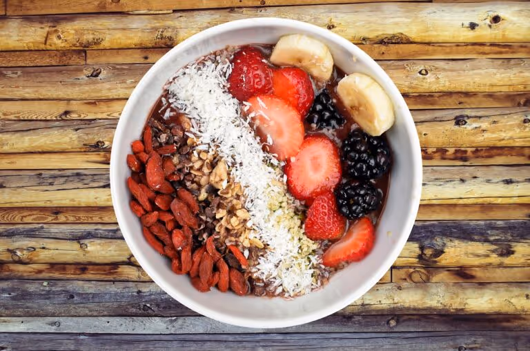 A nutritious breakfast bowl filled with fresh berries, banana slices, nuts, and seeds on a wooden table, representing a high-fiber Mediterranean breakfast with overnight oats