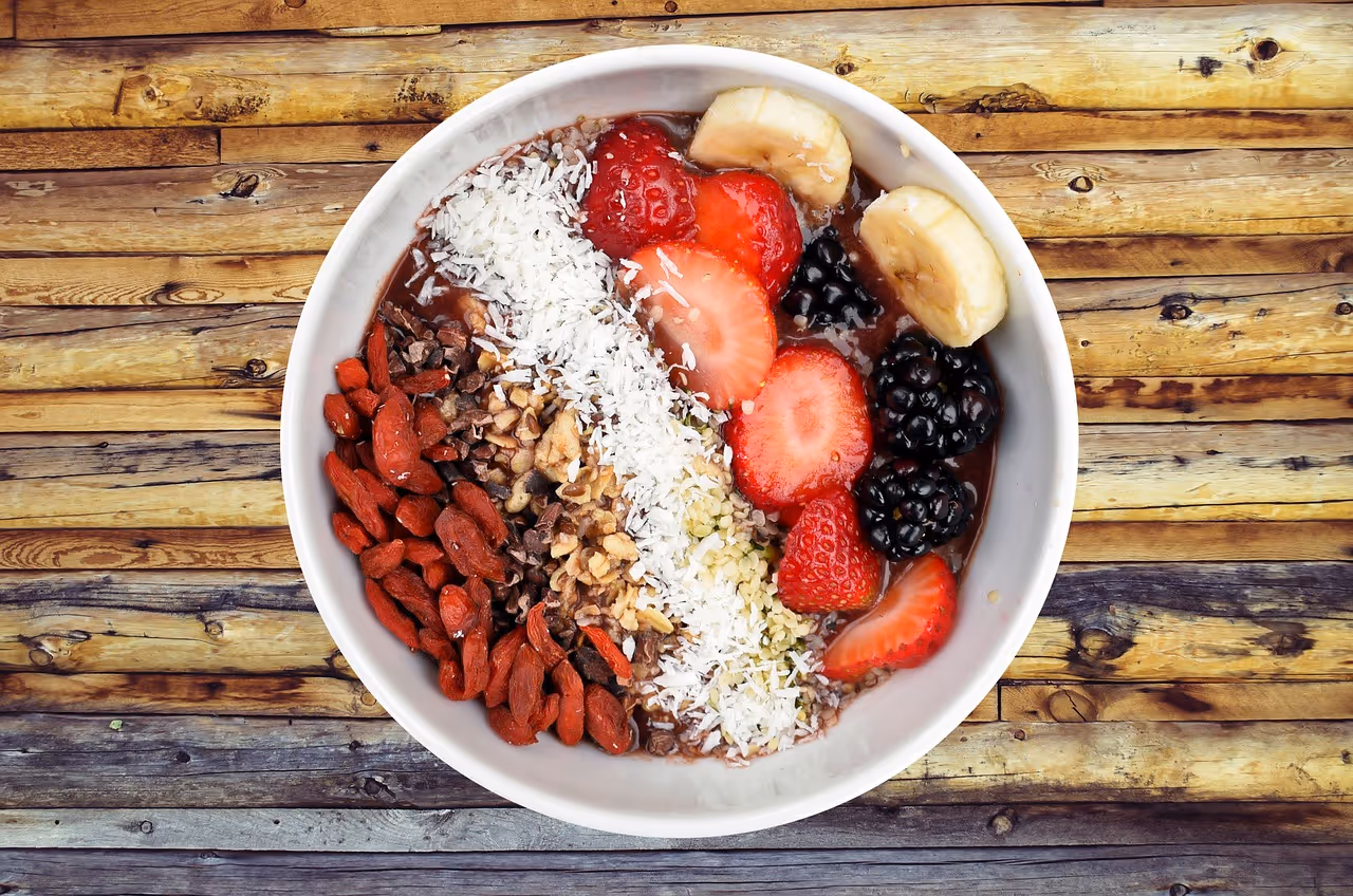 A nutritious breakfast bowl filled with fresh berries, banana slices, nuts, and seeds on a wooden table, representing a high-fiber Mediterranean breakfast with overnight oats