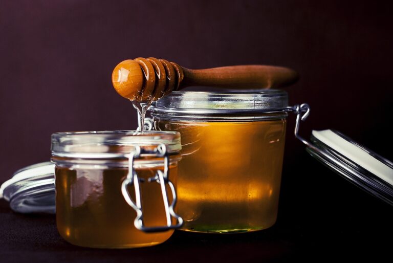 Glass jars of honey with a wooden honey dipper, representing natural honey for skin health, anti-aging, and UV protection benefits