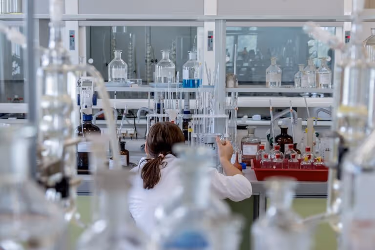 A chemist working in a laboratory with scientific equipment, representing the latest vitamin D research findings on blood levels, supplementation, and immune health.