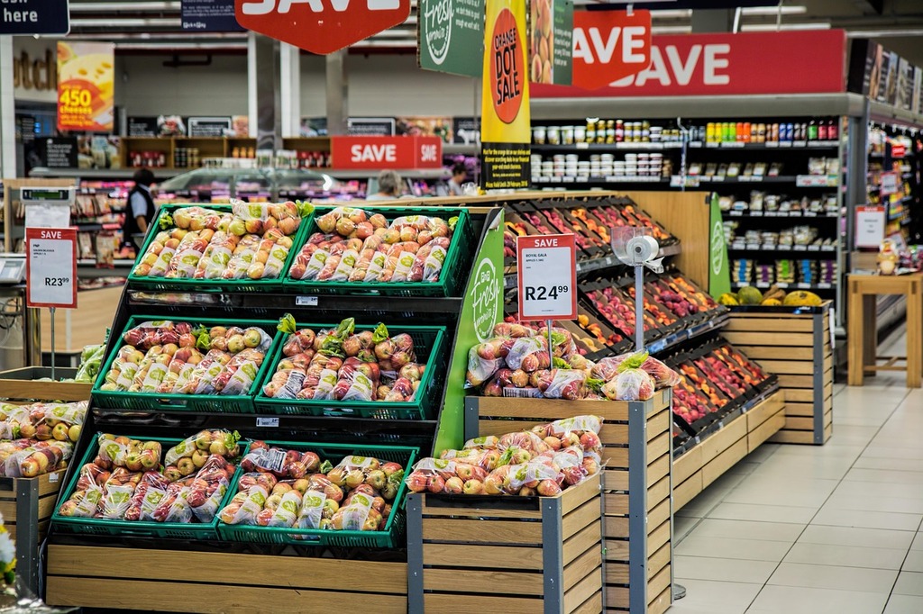 A shopping cart in a grocery store aisle filled with various food products, representing budget-friendly grocery shopping and affordable nutrition choices