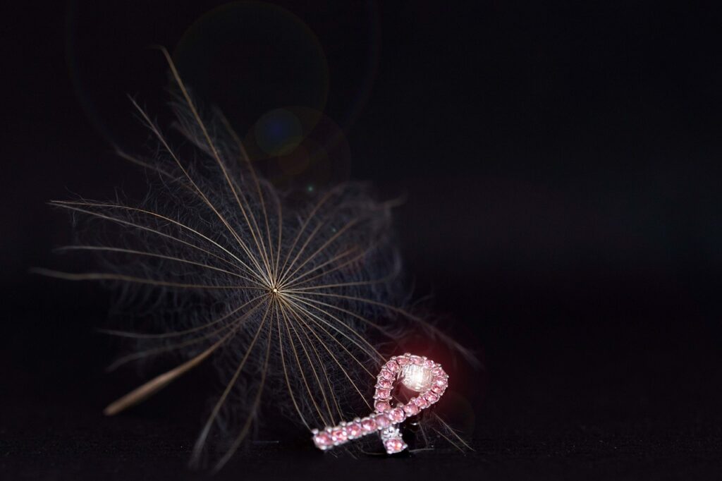 Pink breast cancer awareness ribbon with a delicate dandelion seed, symbolizing hope and the protective effect of pregnancy against breast cancer