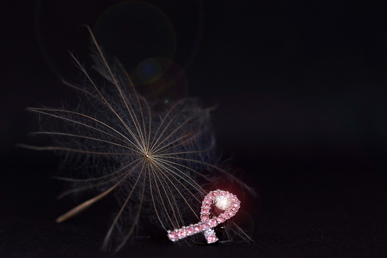 Pink breast cancer awareness ribbon with a delicate dandelion seed, symbolizing hope and the protective effect of pregnancy against breast cancer