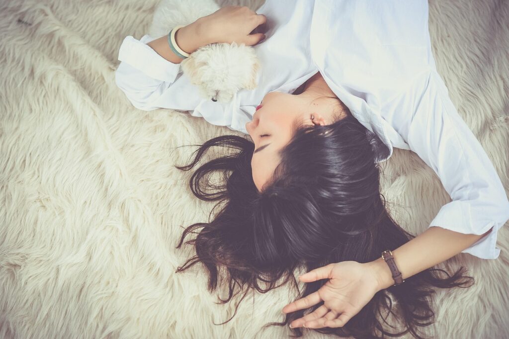 Young woman resting peacefully asleep on a bed with her dog, representing the calming and sleep-promoting benefits of magnesium glycinate supplementation