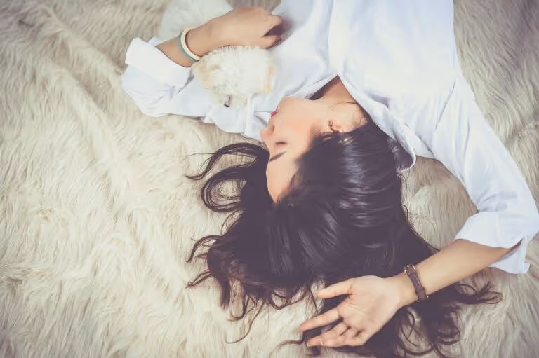 Young woman resting peacefully asleep on a bed with her dog, representing the calming and sleep-promoting benefits of magnesium glycinate supplementation