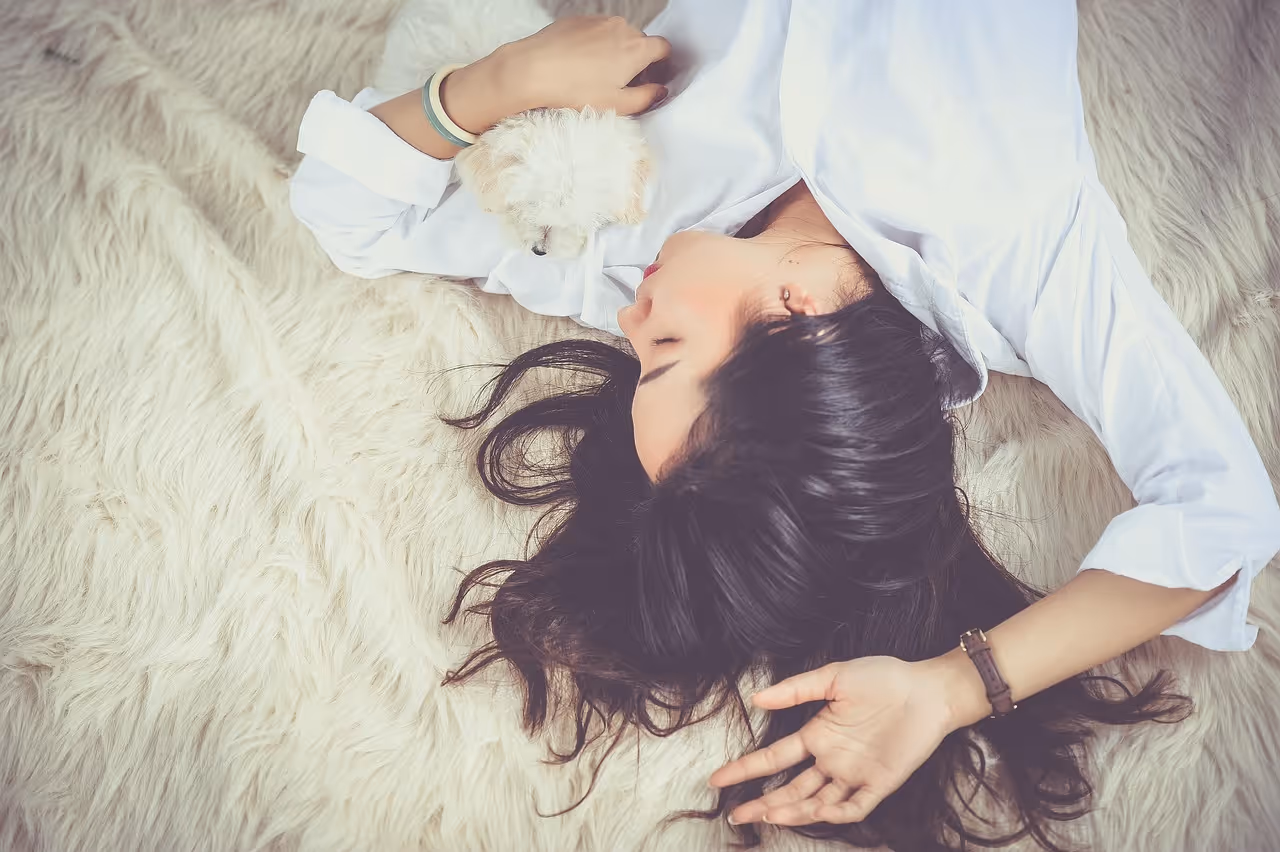 Young woman resting peacefully asleep on a bed with her dog, representing the calming and sleep-promoting benefits of magnesium glycinate supplementation