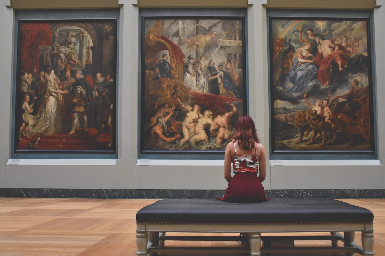 A woman looking at paintings in an art gallery or museum, representing cultural engagement that research shows may help slow biological aging in older adults