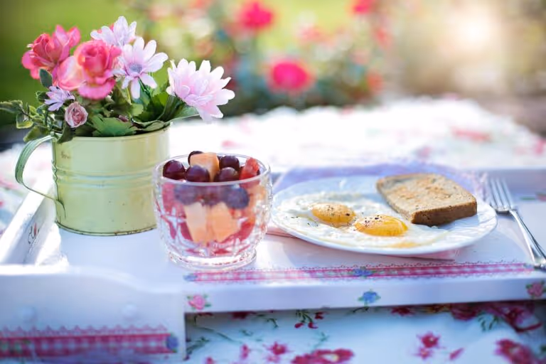 Healthy high protein breakfast with fried eggs, toast, avocado, and fresh fruit on a plate, representing a balanced high protein meal plan for women