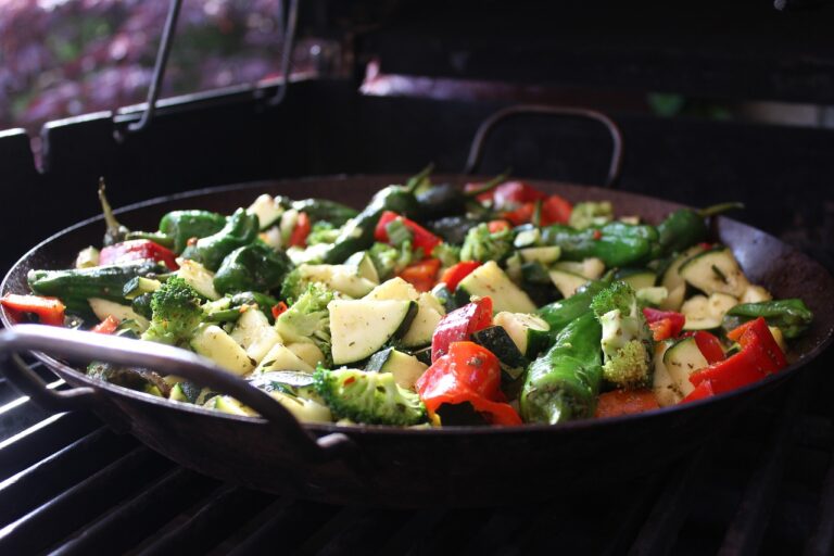 Colorful summer vegetables including zucchini, bell peppers, and broccoli being cooked in a skillet pan — healthy summer skillet dinner concept