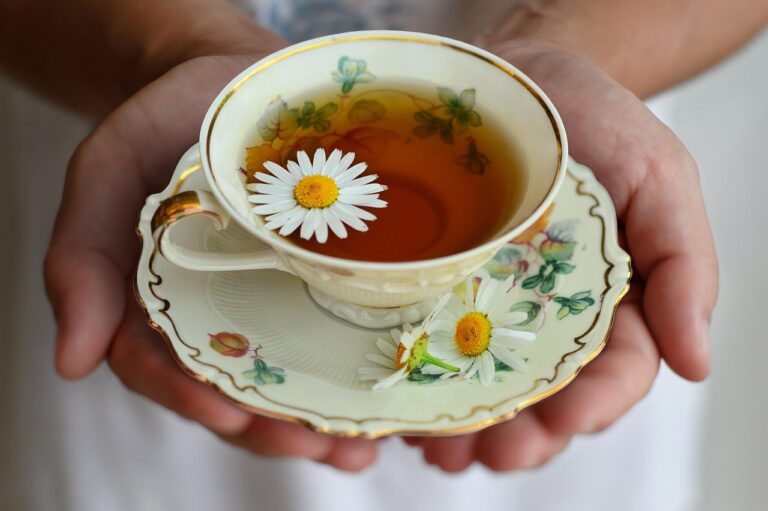 A warm cup of chamomile tea with chamomile flowers on a ceramic saucer, creating a calming evening mood for relaxation and sleep