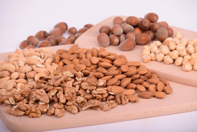 A variety of mixed nuts including almonds, walnuts, cashews, and hazelnuts on a wooden surface, representing healthy high-protein no-sugar snack options for summer