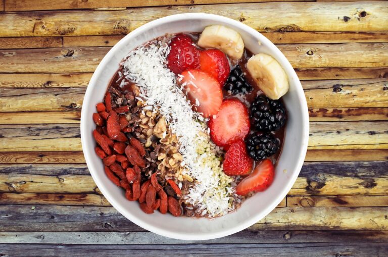A vibrant breakfast bowl filled with fresh strawberries, raspberries, banana slices, muesli and nuts — perfect for a high fiber breakfast supporting weight loss and gut health.