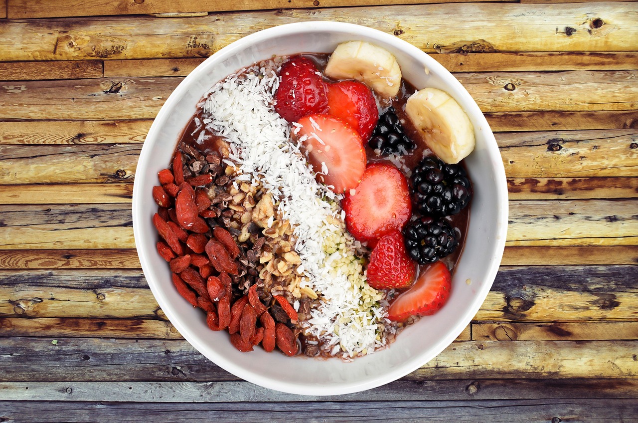 A vibrant breakfast bowl filled with fresh strawberries, raspberries, banana slices, muesli and nuts — perfect for a high fiber breakfast supporting weight loss and gut health.
