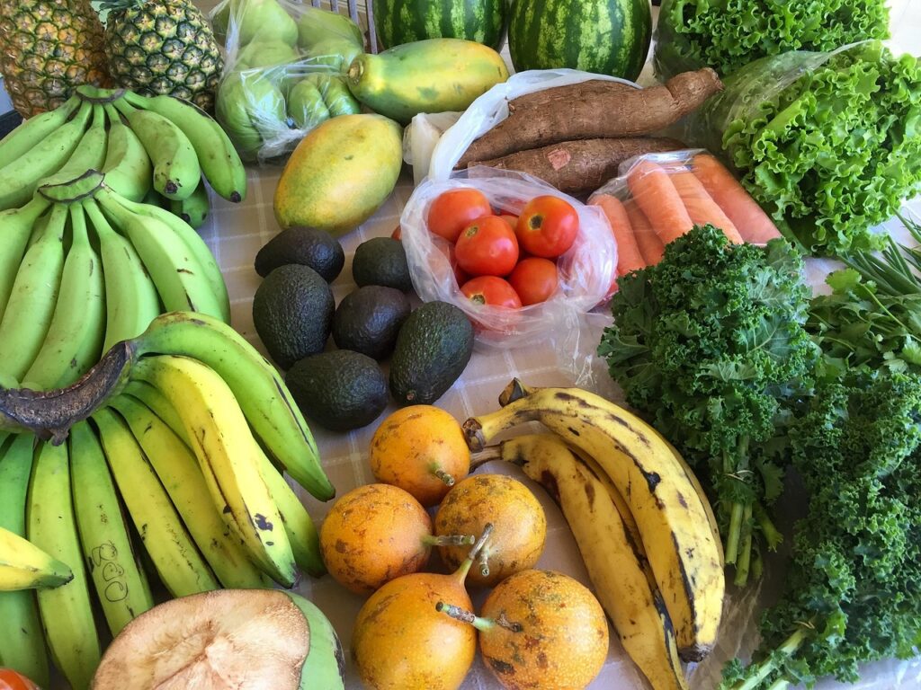 Colorful assortment of fresh fruits and vegetables on a wooden table, representing anti-inflammatory foods for a healthy grocery list including berries, citrus, leafy greens, and tomatoes