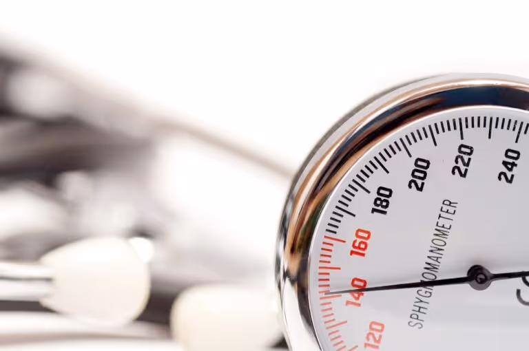Close-up of a blood pressure sphygmomanometer gauge and cuff on a white background, representing hypertension management and monitoring for heart health.