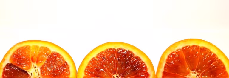 Fresh blood oranges sliced in half on a dark surface, representing healthy fruit choices for blood sugar stability and steady energy