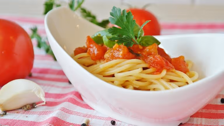 Spaghetti with rich homemade tomato sauce surrounded by fresh ripe tomatoes, representing easy homemade pasta sauce made from simple ingredients