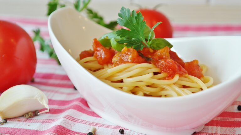 Spaghetti with rich homemade tomato sauce surrounded by fresh ripe tomatoes, representing easy homemade pasta sauce made from simple ingredients