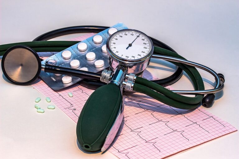Blood pressure monitor, stethoscope, and ECG heart rhythm chart on a table with medication, representing tools for monitoring evening blood pressure and hypertension management
