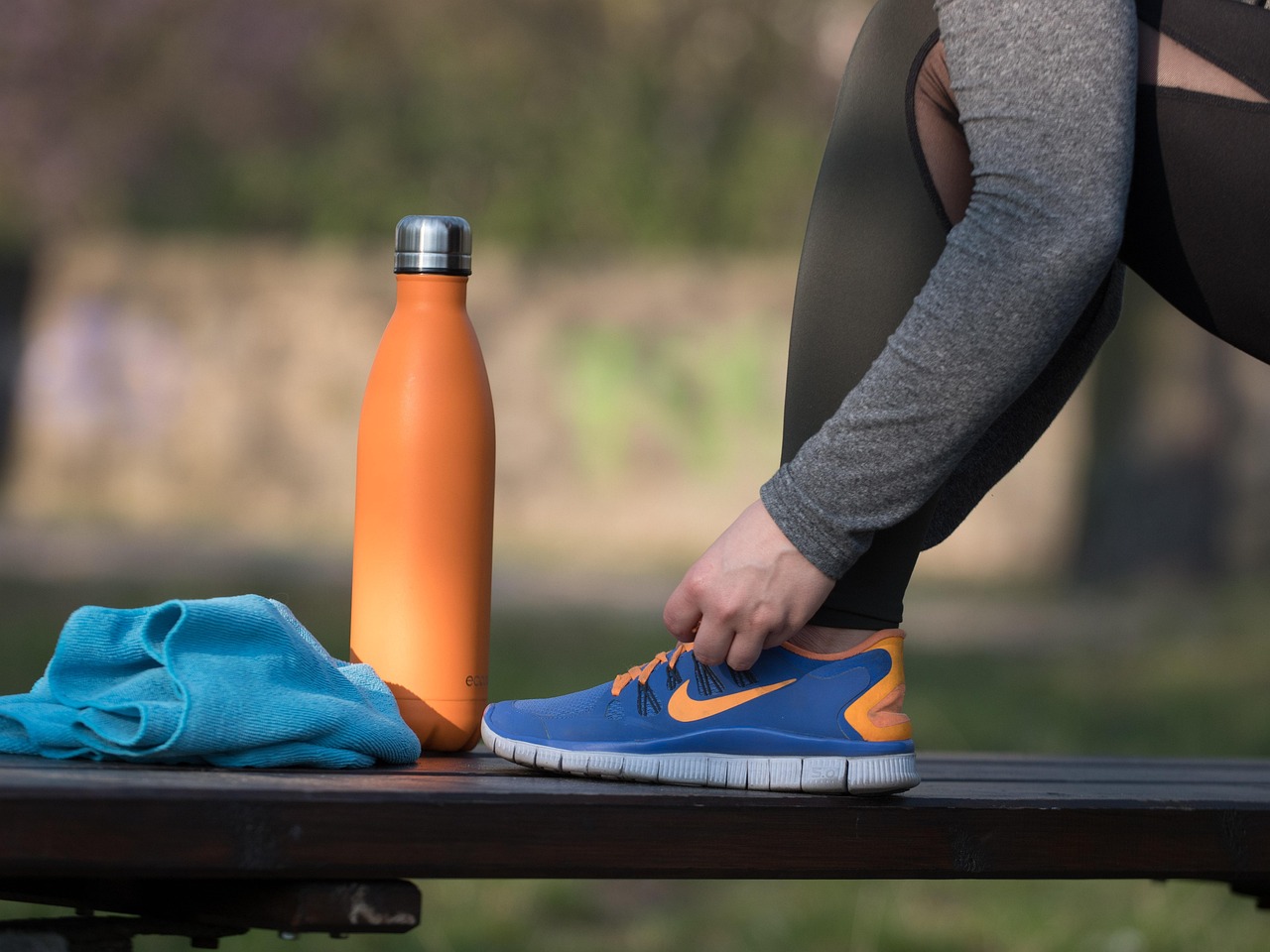 Woman with athletic wear, water bottle and towel preparing for exercise — representing a healthy lifestyle approach to PCOS weight loss through fitness, strength training, and movement