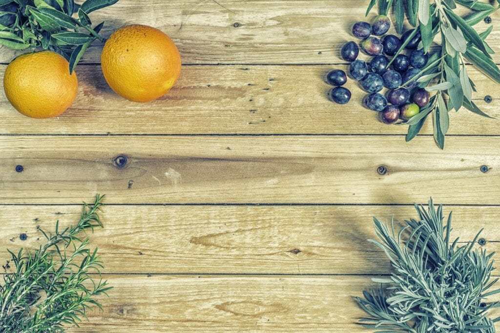 Mediterranean diet ingredients including olives, olive oil, oranges and fresh herbs arranged on a wooden surface, representing brain-healthy eating patterns