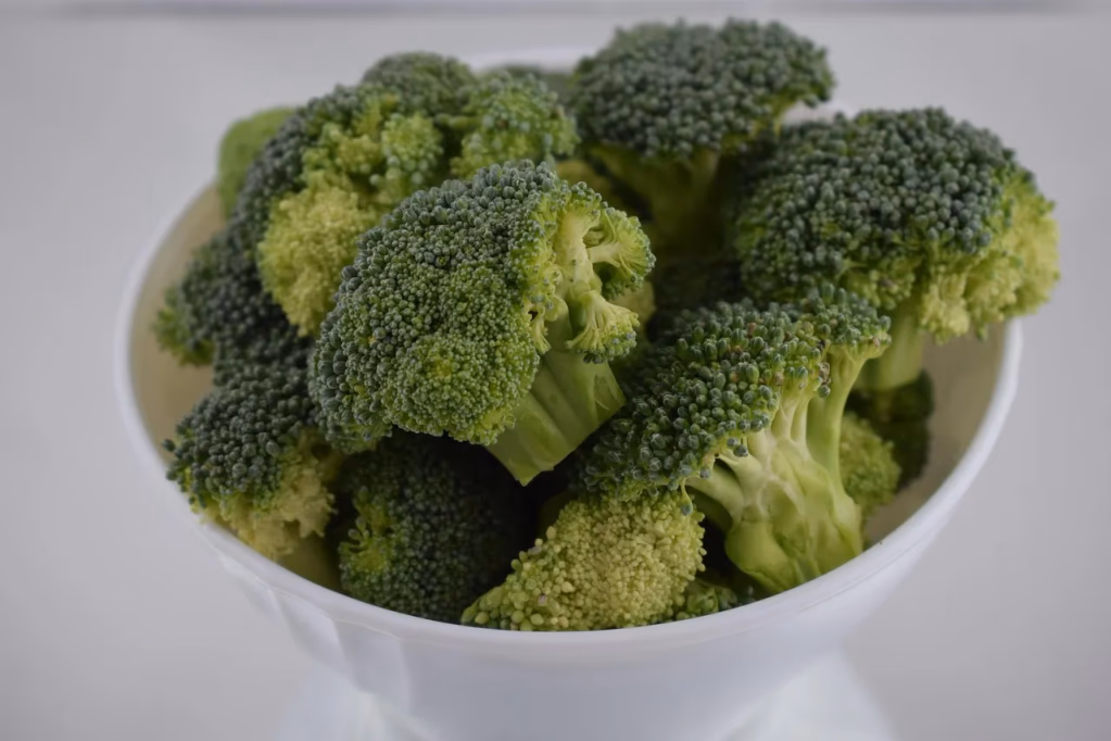 Fresh green broccoli florets arranged in a white bowl, perfect for healthy broccoli salad recipes with nutritious cruciferous vegetables