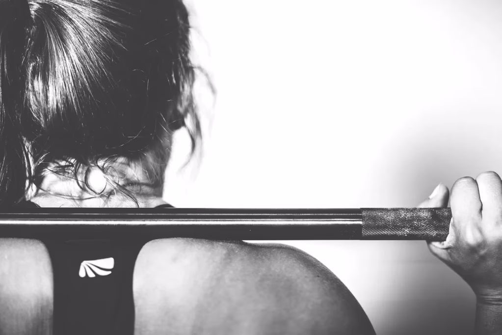 A woman performing a barbell squat exercise in a gym, demonstrating strength training for women for heart health and longevity